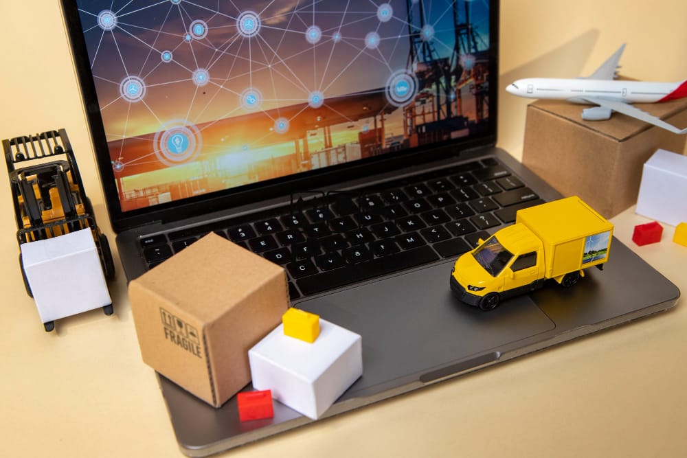 Laptop showing logistics network, toy trucks, and packages. Efficient logistics services. -Shipping Company in Egypt